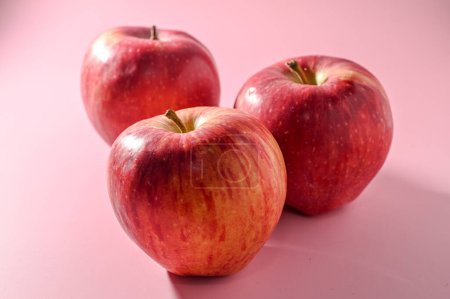 Téléchargez les photos : Trois pommes rouges sur fond rose - en image libre de droit