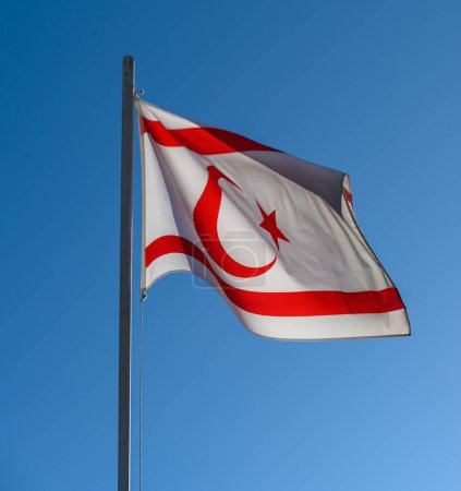 Bandera de la República Turca del Norte de Chipre en el cielo azul con nubes de fondo
