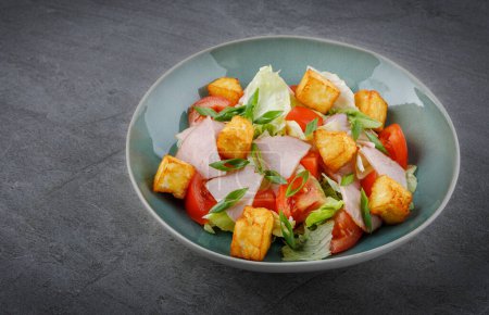 Großaufnahme von Salat mit Schinken und Halloumi-Käse in einer Schüssel auf dem Tisch