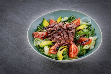 Salade savoureuse - longe de veau rôtie, avocat, ?ufs durs et légumes frais sur table en pierre