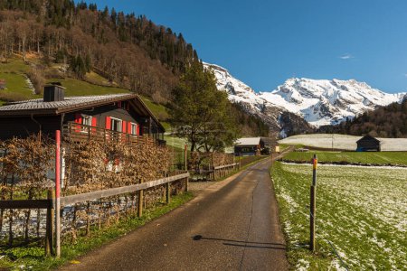Foto de Carretera estrecha con casas y vista al monte nevado. Saentis, Wildhaus-Alt St. Johann, Toggenburg, Canton St. Gallen, Suiza - Imagen libre de derechos