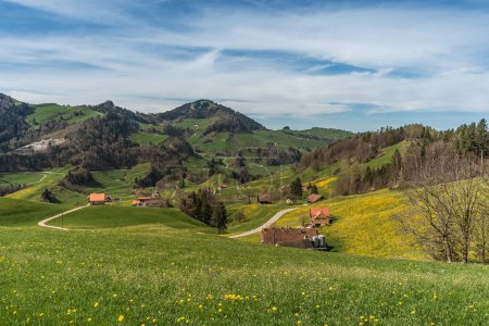 Paisaje montañoso en el Appenzellerland con casas de campo y prados de diente de león en primavera, Cantón de Appenzell Innerrhoden, Suiza