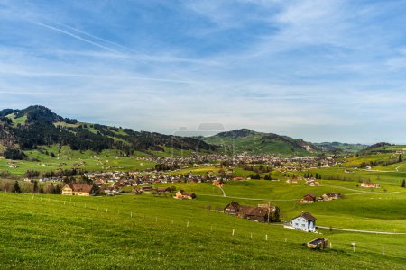 Hilly landscape in the Appenzellerland with farm houses and green meadows, view to the village of Appenzell, Canton of Appenzell Innerrhoden, Switzerland