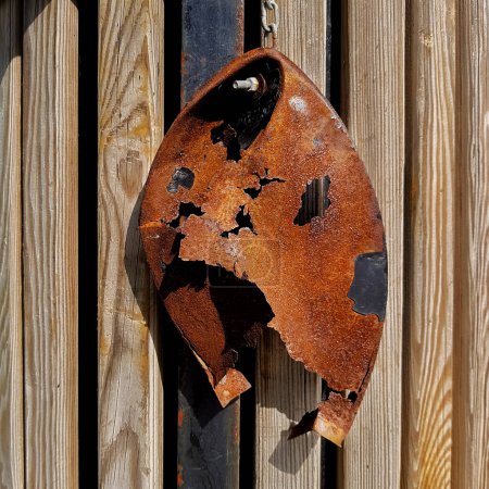 Photo for Rusted piece of metal hanging from a wooden post - Royalty Free Image
