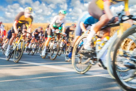 Téléchargez les photos : Groupe de Cyclistes Pendant une Course ensoleillée, mtion floue, ciel couvert en arrière-plan - en image libre de droit