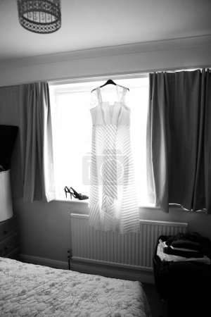 Foto de Vestido de novia colgando contra ventana - Imagen libre de derechos