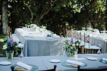 Téléchargez les photos : Belles tables de mariage avec des fleurs et vaisselle. Cadre pour mariage en plein air - en image libre de droit