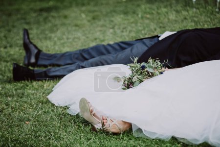 Téléchargez les photos : Gros plan de mariée et marié couché sur l'herbe - en image libre de droit