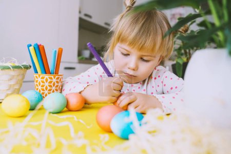 Foto de Smiling little girl with colorful eggs preparing for Easter Holiday. Kids painting easter eggs. Creative background for preschool and kindergarten. Family traditions and symbols of celebration. - Imagen libre de derechos