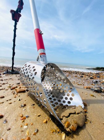 Photo for Metal detecting equipment detector and sand scoop on the beach with ocean sand waves and sky behind background with copy space - Royalty Free Image