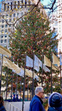 Photo for New York, NY, USA - Dec 4, 2022: The 2022 Christmas tree stands adorned with ornaments and flags blowing in the wind at Rockefeller Center in midtown. - Royalty Free Image