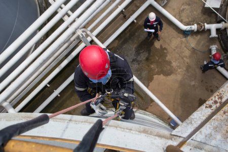 Téléchargez les photos : Inspection de l'accès par câble des travailleurs masculins de l'industrie des réservoirs de stockage d'épaisseur sous le pipeline - en image libre de droit