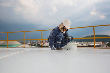 Téléchargez les photos : Travailleur masculin sont pour l'inspection à ultrasons épaisseur plaque de toit dessus du réservoir de stockage - en image libre de droit