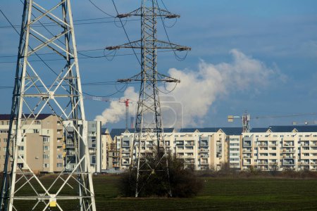 Téléchargez les photos : Bucarest, Roumanie - 13 décembre 2022 : Cheminée de la centrale électrique de Bucarest CET Sud pollue avec de la fumée vue de loin au-dessus de nombreux blocs d'appartements dans le sud de Popesti-Leordeni. - en image libre de droit