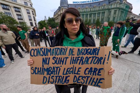 Téléchargez les photos : Bucarest, Roumanie. 20 avril 2024 : Une femme tient une pancarte qui dit : "Les toxicomanes ne sont pas des criminels ! Changer les lois qui détruisent les destins "devant une foule éclair d'une minute à 16h20, sur la place de l'Université à Bucarest, contre les lois votées par les Roms - en image libre de droit