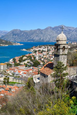 Téléchargez les photos : Kotor, Montenegro, Europe. Bay of Kotor on Adriatic Sea. Church, roofs of the historical buildings in the old town. Bay and mountains in the background. Clear blue sky, sunny day. - en image libre de droit