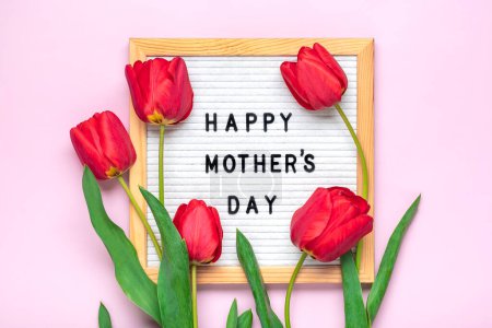 Tablero de fieltro con texto Feliz Día de la Madre, tulipanes rojos ramo en rosa saludo de fondo tarjeta de vacaciones Flat lay Top view.