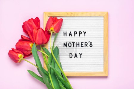 Téléchargez les photos : Feutre avec texte Happy Mothers day, bouquet de tulipes rouges sur fond rose carte de vœux de fin d'année Flat lay Vue du dessus. - en image libre de droit