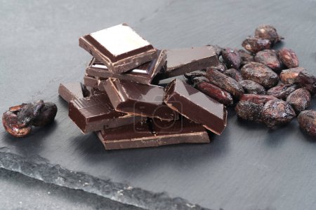 Photo for Broken dark chocolate and cocoa beans on a table - Royalty Free Image