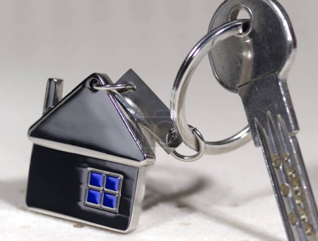 Téléchargez les photos : Symbole de la maison avec des clés argentées sur fond abstrait. Concept immobilier - en image libre de droit