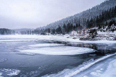 Fairytale landscape with snowy mountain slopes and frozen water of Beglik dam in Rila mountain, Bulgaria in frosty winter morning.