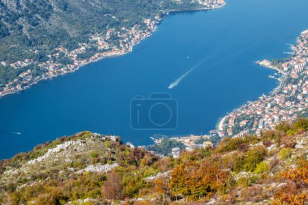 Foto de Increíble vista desde arriba de los barcos a motor en el mar azul cielo de la Bahía de Kotor en Montenegro, con una pintoresca costa, techos rojos de casas y el puerto deportivo con barcos. - Imagen libre de derechos