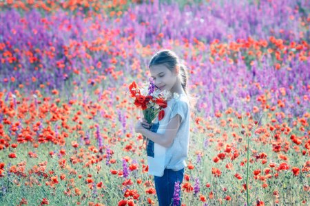 Téléchargez les photos : Belle fille tenant grand bouquet avec des coquelicots sur le fond d'un champ de printemps coloré - en image libre de droit