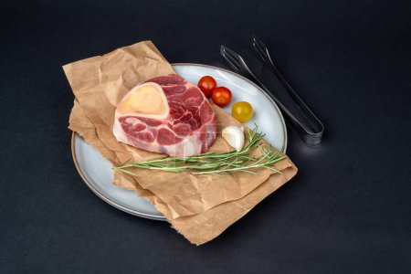 Foto de Filete cruzado crudo de caña de ternera, verduras y condimentos para preparar el italiano Osso Buco en una tabla de cortar de madera redonda - Imagen libre de derechos