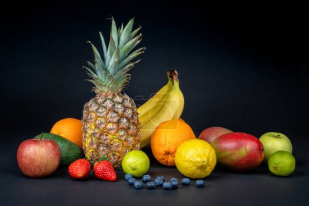 Foto de Still life with variety of fresh and ripe fruits arranged on a dark background. Fitness concept, diet, healthy lifestyle. Concept for elegant presentation of healthy food. - Imagen libre de derechos