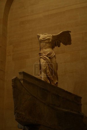 Photo for A majestic ancient Greek marble statue of the goddess Nike. The sculpture captures movement and grace, depicting Nike with her wings spread wide as if she has just landed on the prow of a ship, which serves as the base of the statue. - Royalty Free Image