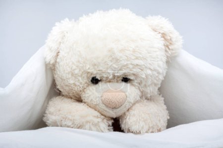Photo for Toy Teddy Bear under the blanket on bed - Royalty Free Image
