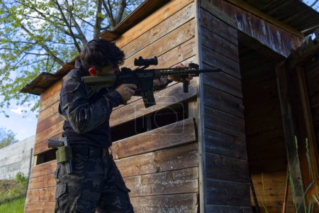 a young sniper aims at a house from the woods. High quality photo