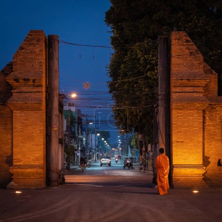 Foto de Chiang Mai, Tailandia - 4 de febrero de 2023: Los monjes caminan a través de la Puerta de Tha Phae para pedir limosna por la mañana. La antigua puerta de la ciudad es un lugar famoso y un destino por la mañana, según las creencias del budismo en Tailandia.. - Imagen libre de derechos