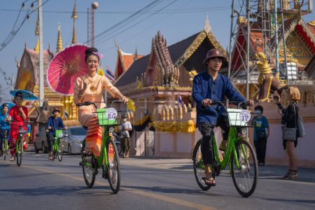 Foto de Chiang Mai, Tailandia - 20 de enero de 2023: Mujeres bonitas sosteniendo hermosos paraguas con trajes tradicionales y montando bicicletas espectáculo anual en San Kamphaeng, Bosang festival de paraguas. - Imagen libre de derechos