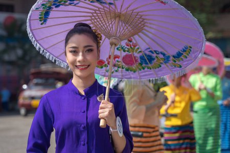 Photo for Chiang Mai, Thailand - January 20, 2023: Pretty women holding beautiful umbrellas in traditional costumes smiled at the participants of the annual event show San Kamphaeng, Bo sang umbrella festival. - Royalty Free Image
