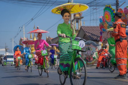 Foto de Chiang Mai, Tailandia - 20 de enero de 2023: Mujeres bonitas sosteniendo hermosos paraguas con trajes tradicionales y montando bicicletas espectáculo anual en San Kamphaeng, Bosang festival de paraguas. - Imagen libre de derechos