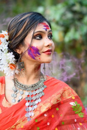 Porträt eines hübschen jungen Mädchens in traditionellem indischen Sari und Schmuck, das mit Farben auf dem Holi-Fest spielt, einem beliebten hinduistischen Fest, das in ganz Indien gefeiert wird.