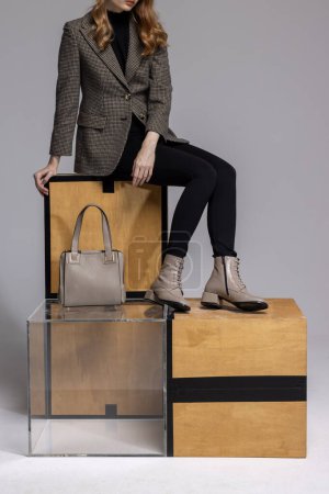 Frau mit Lederhandtasche und Lederstiefeln. Modischer Luxus im Atelier. 