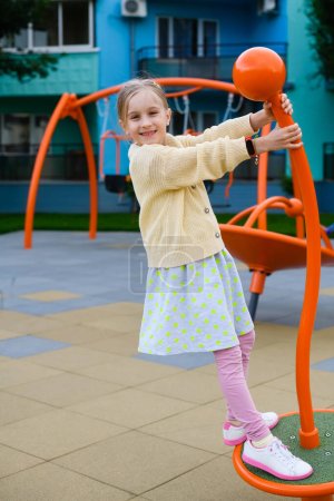 Foto de Niña niña primaria niño jugando en la ciudad urbana colorido moderno parque infantil de metal, fin de semana de ocio familiar - Imagen libre de derechos