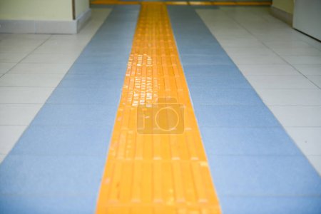 Photo for Perspective yellow tactile strip for cane or foot of blind person, close-up. - Royalty Free Image
