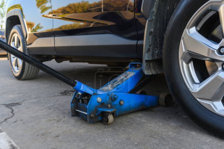 Foto de Jack de piso hidráulico azul de cerca. Cambio de neumáticos en un centro de servicio. - Imagen libre de derechos