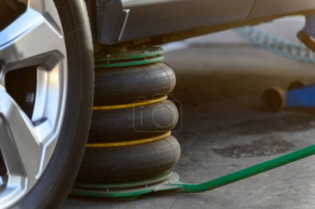 Foto de Un gato neumático soporta el vehículo mientras cambia los neumáticos. Primer plano. - Imagen libre de derechos