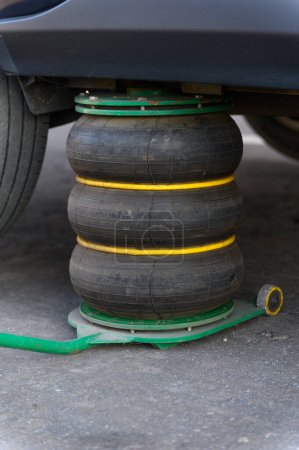 Foto de Un gato neumático soporta el vehículo mientras cambia los neumáticos. Primer plano. - Imagen libre de derechos