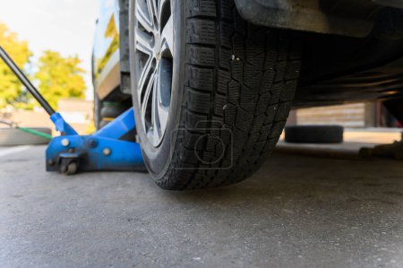 Foto de Jack de piso hidráulico azul de cerca. Cambio de neumáticos en un centro de servicio. - Imagen libre de derechos