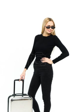 Téléchargez les photos : Jolie jeune femme avec une valise sur fond blanc. Fille en vêtements noirs. - en image libre de droit