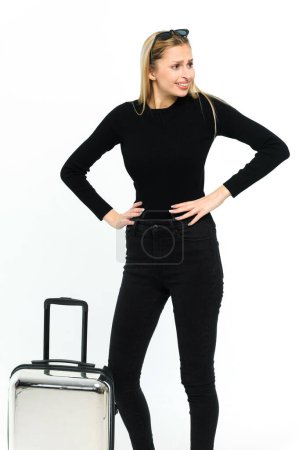 Téléchargez les photos : Jolie jeune femme avec une valise sur fond blanc. Fille en vêtements noirs. - en image libre de droit