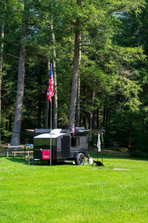 Photo for Cooksburg PA - September 17, 2022: Small teardrop travel trailer parked at a state campground site with American flag. High quality photo - Royalty Free Image