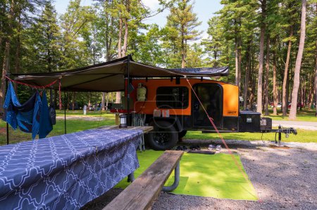 Photo for Cooksburg PA - September 17, 2022: Small orange teardrop travel trailer with 270 degree awning at a state campground site. High quality photo - Royalty Free Image