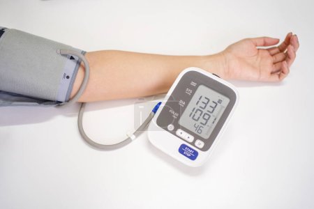 Woman measures blood pressure, with copy space on white background 