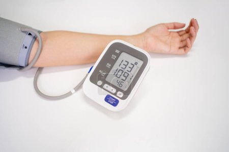 Mujer compruebe el monitor de presión arterial y el monitor de frecuencia cardíaca con manómetro digital con espacio de copia sobre fondo blanco.